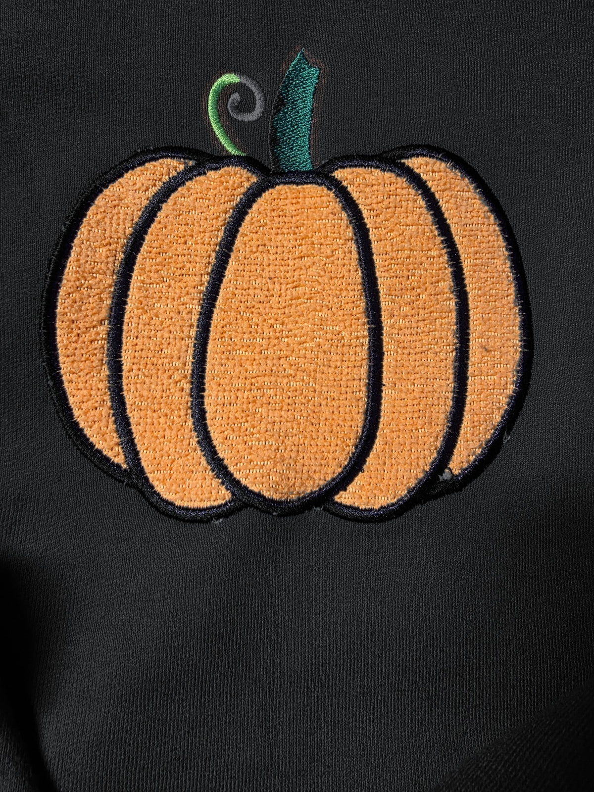 Close-up of fuzzy embroidered pumpkin on Black (mockup)