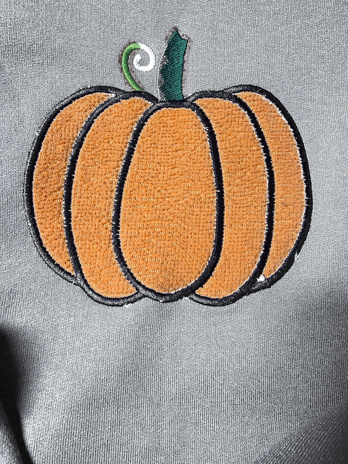 Close-up of fuzzy embroidered pumpkin on Gray (mockup)