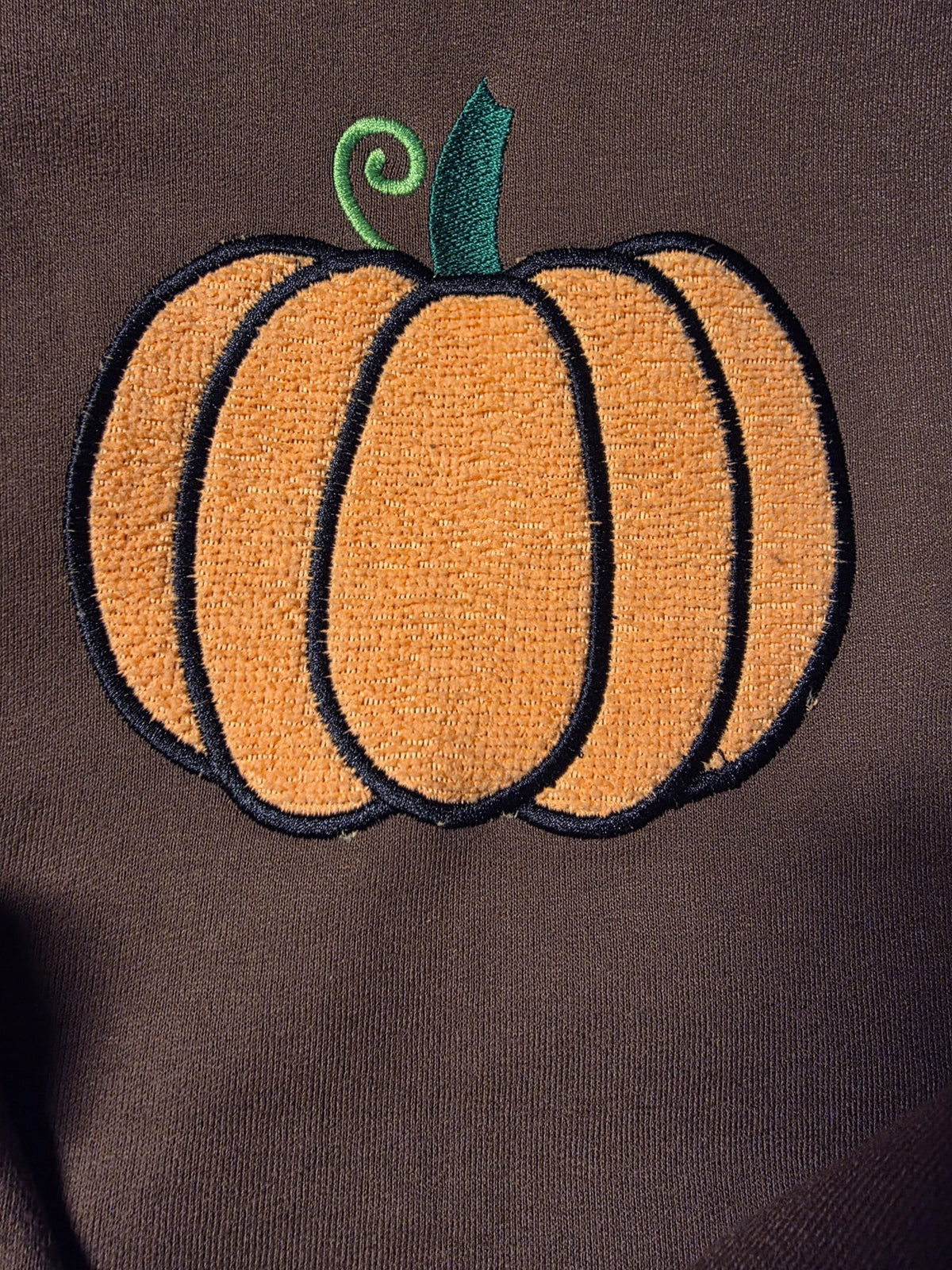Close-up of the fuzzy chenille-style embroidered pumpkin on Chocolate Brown